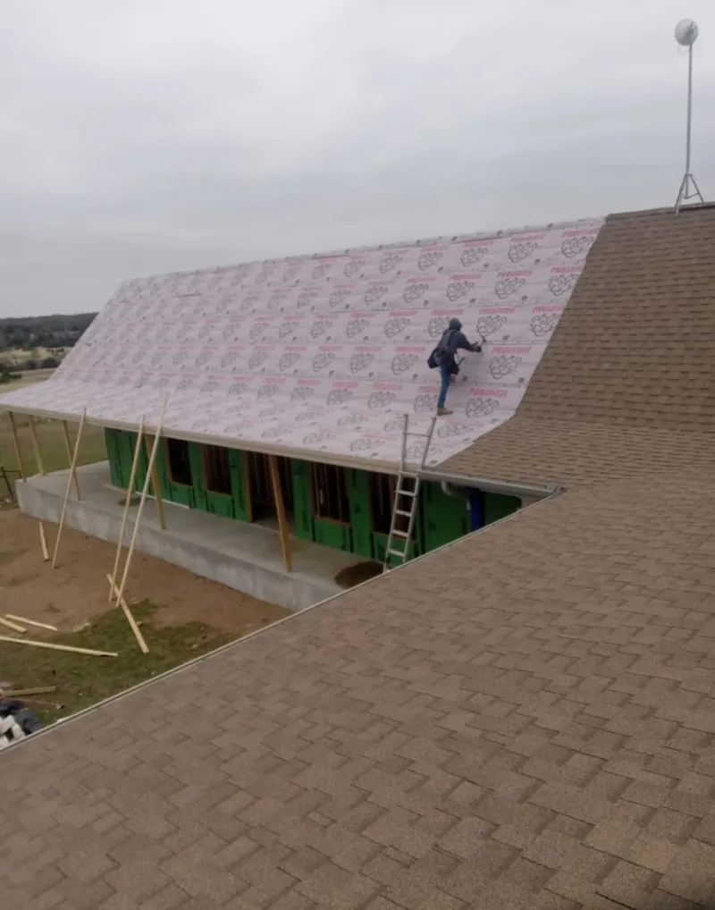 Worker preparing underlayment for a metal roof installation in Houston